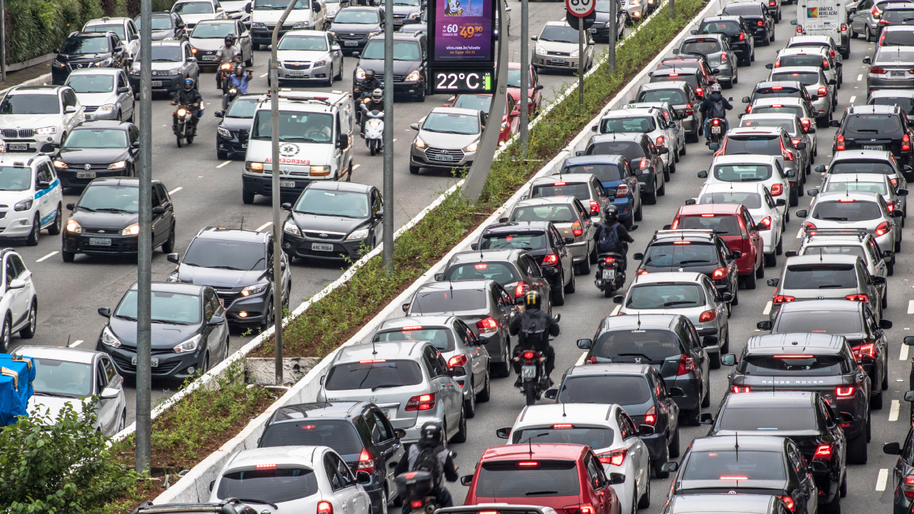 Trânsito intenso em uma avenida brasileira durante o horário de pico com muitos veículos.