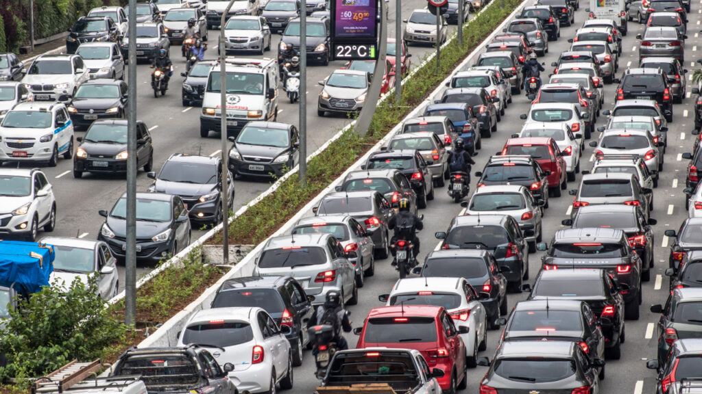 Trânsito intenso em uma avenida brasileira durante o horário de pico com muitos veículos.