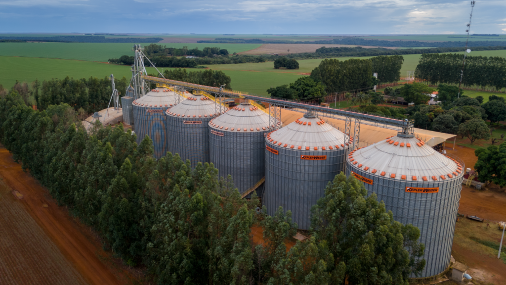 Vista aérea de grandes estruturas para guardar grãos da Kepler Weber em área agrícola.