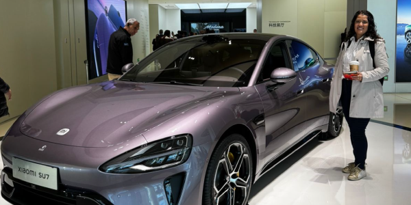 Gerente de Projetos Mobi7 Localiza ao lado de carro tecnológico em sua visita à China (representando inovação em gestão de frotas com IA).